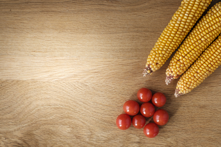 wooden table with tomatoes and  corn on the cob with copy spaceの写真素材