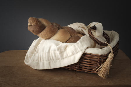 3 types interwoven bread in a wicker basket stands on a wooden tableの写真素材