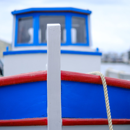 typical brightly colored Greek fishing boat with rope is fixed to the quayの写真素材