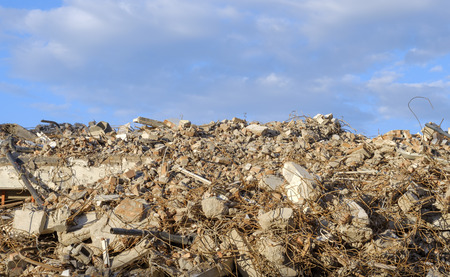 Large mountain demolition of building blocks and curved iron against a blue skyの写真素材