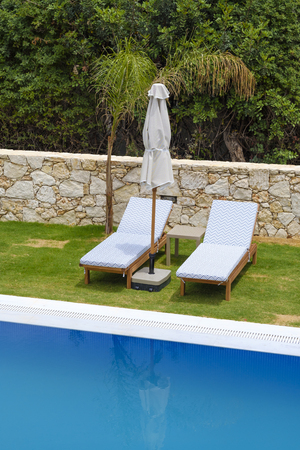 Two sunbeds and a parasol are located by the poolの写真素材