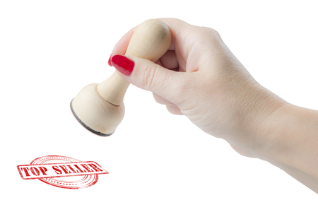 Hand holding a rubber stamp with the words top seller isolated on a white backgroundの写真素材