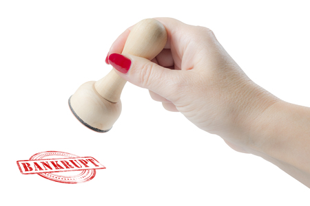 Hand holding a rubber stamp with the word bankrupt isolated on a white backgroundの写真素材