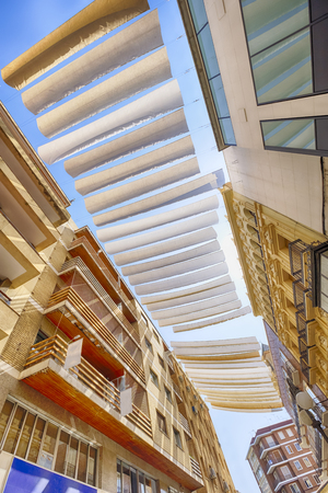 strips or fabric suspended high between the buildings provide protection from the sun in the streets of córdoba spainの写真素材