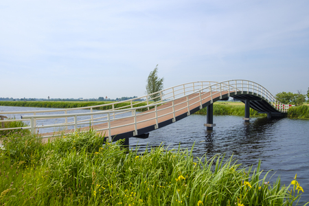 modern designed pedestrian bridge spans over the water in an arcの写真素材