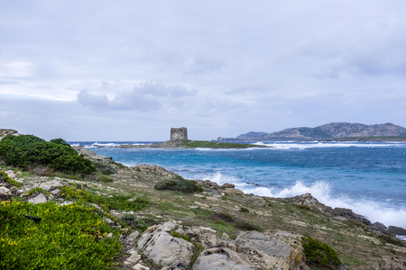 a view of the the Torre della Pelosa tower and the Isola Piana island in the background in stormy weather,stintino, sardinia,italyの写真素材