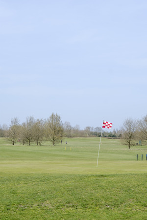 A red and white checkered golf course flagstick on a putting green.の写真素材