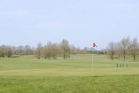 A red and white checkered golf course flagstick on a putting green.の写真素材