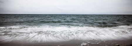 artistic moving blurred background of the foam of the waves that wash up on the beachの写真素材