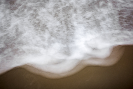 artistic moving blurred background of the foam of the waves that wash up on the beachの写真素材