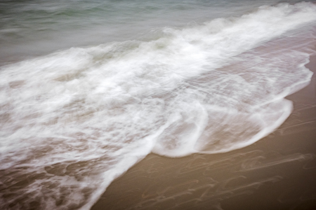 artistic moving blurred background of the foam of the waves that wash up on the beachの写真素材