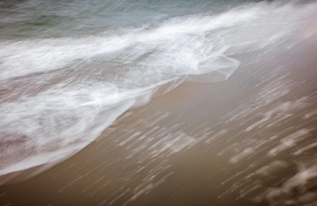 artistic moving blurred background of the foam of the waves that wash up on the beachの写真素材