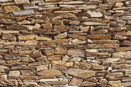 wall of yellow colored slate stones that are expertly stacked without cementの写真素材