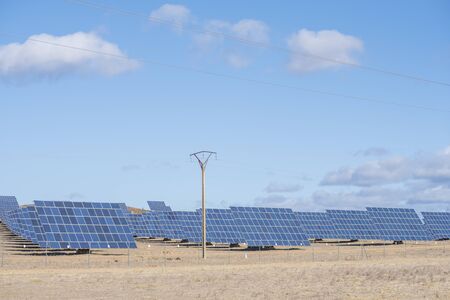 solar panels with tracker field for generating sustainable energy with an electric mast in the foreground for transporting the generated electricity, extremadura, spainの写真素材