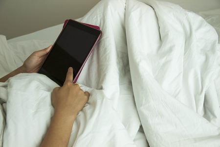 lifestyle young girl relaxing morning bed tabletの写真素材