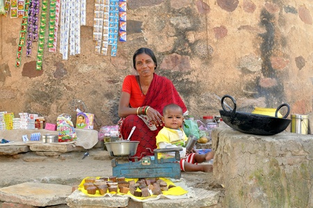 Khajuraho, India - November 27, 2009 - Hindu woman with her child, selling sweets, biscuits, cigarettesのeditorial素材