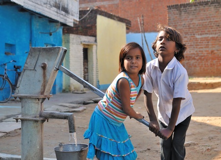 Khajuraho, India - November 27, 2009 - Children pumping water into the bucket. In many parts of India, no current water in their homes.のeditorial素材