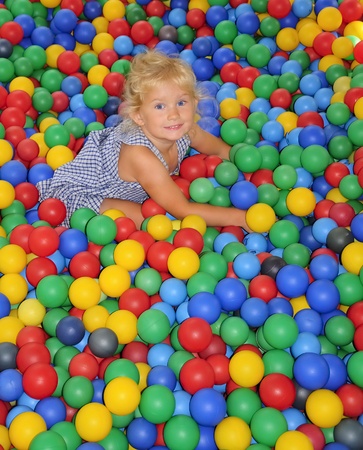 Happy little girl playing in balls  の写真素材