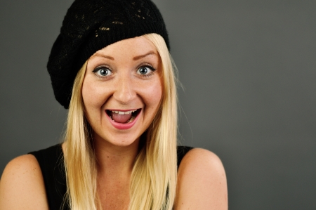 Young blonde happy woman on grey wall 