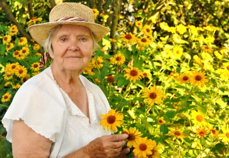 Senior woman with flowers in garden の写真素材