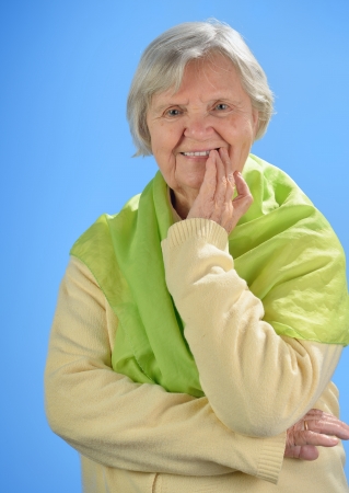 Senior happy woman with grey hairs against blue background の写真素材
