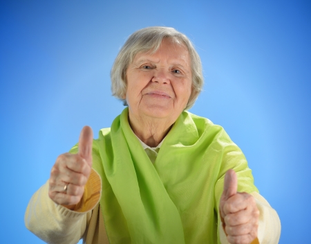 Senior happy woman with grey hairs against blue background の写真素材