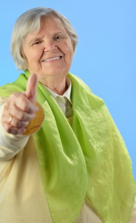 Senior happy woman with grey hairs against blue background の写真素材