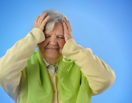 Senior worried woman with grey hairs against blue background の写真素材