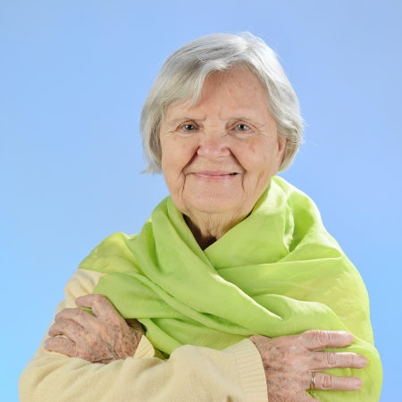 Senior happy woman with grey hairs against blue background の写真素材