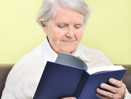 Senior woman reading book in home の写真素材