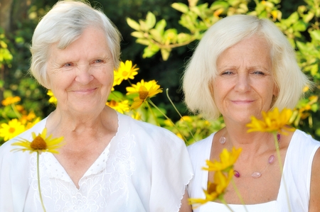 Senior and mature women in garden full of flowers の写真素材