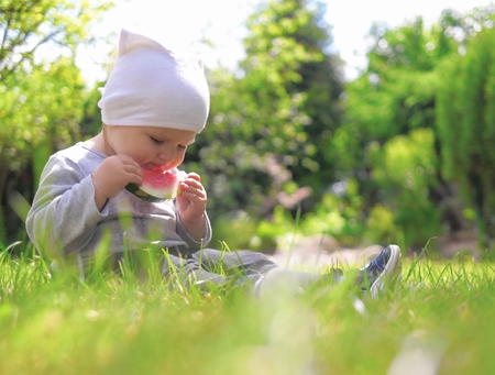 Little child eating watermelon on grass の写真素材