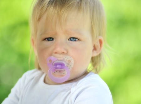Cute baby with soother in his mouth, outdoors 