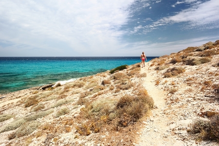 Young girl walking through the beautiful rocky coastline with turquoise sea  Majorca の写真素材