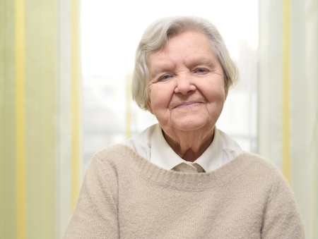 Senior happy woman in her home with window on background.の写真素材