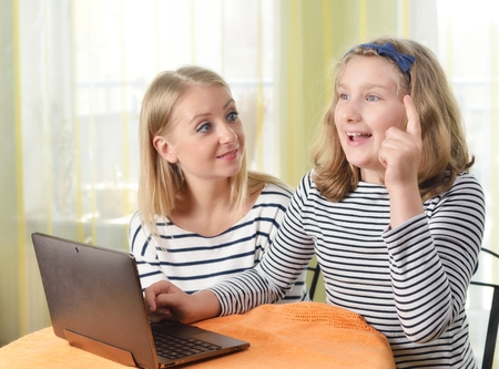 Happy girl and grandmother using a laptop in home.の写真素材