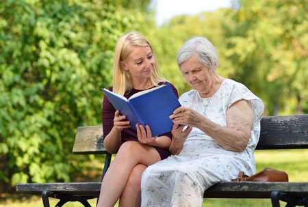 Young woman reading a book elderly woman in the park.の写真素材