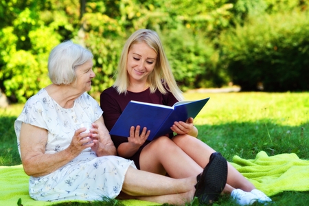 Young woman reading a book elderly woman in the park.の写真素材