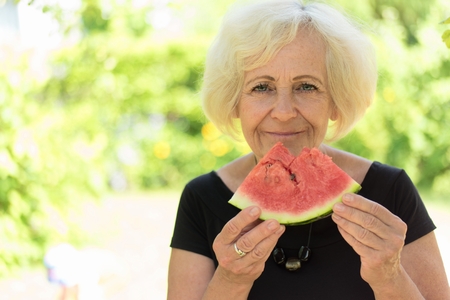 Mature woman eating watermelon.の写真素材