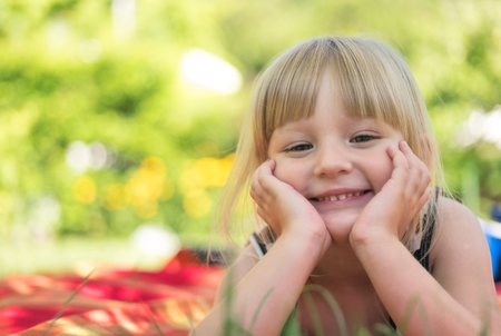 Little girl lying in grass in park.の写真素材
