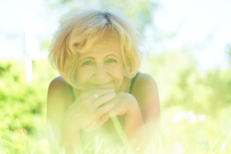 Happy middle-aged woman lying in the grassの写真素材