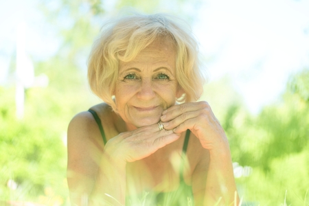 Happy middle-aged woman lying in the grassの写真素材