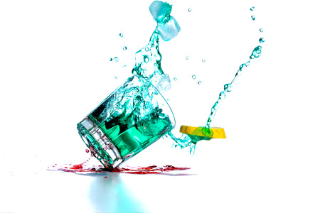 Drink glass with cocktail drops and spillsの写真素材