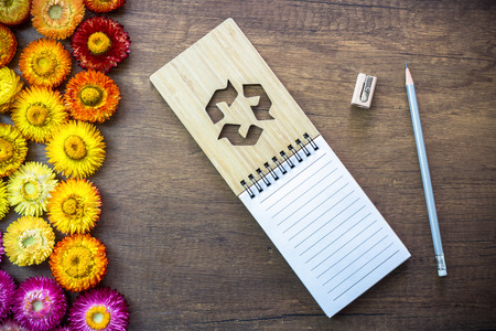 Opened blank page notebook on wood table with pencil , sharpener and straw flowers, Recycle sign on wood cover.の写真素材