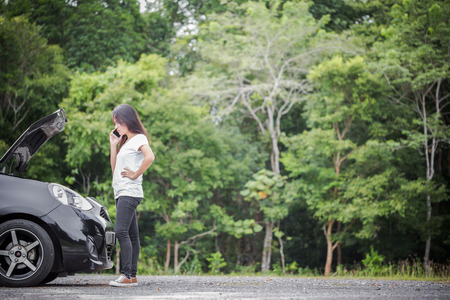 Broken down car and asian woman calling car mechanicの写真素材