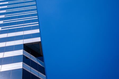 Picture of a glass building office with a clear blue skies, taking pictures from an oblique view and...