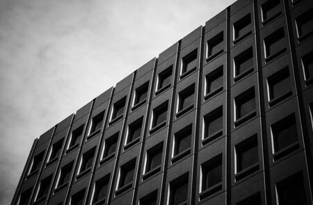 Black office building with many windows and black clouds. Somewhere in Tokyo, Japan gives a modern...