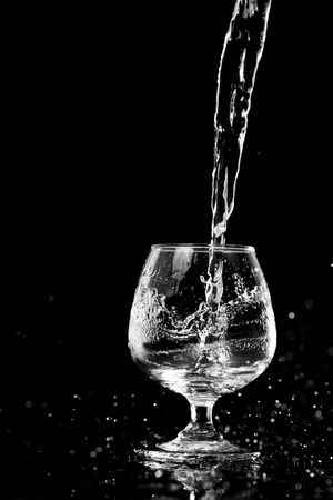 Water splashing in a glass, isolated on blackの写真素材