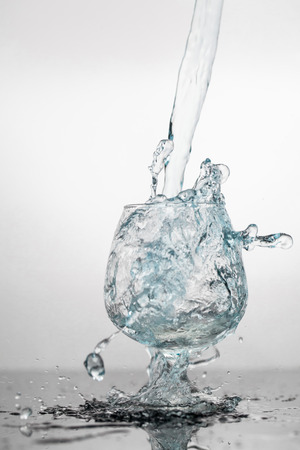 Water splashing in a glass, isolated on blackの写真素材