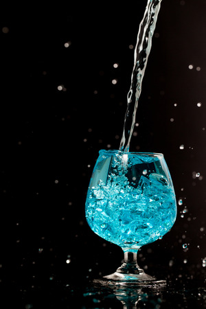 Water splashing in a glass, isolated on blackの写真素材